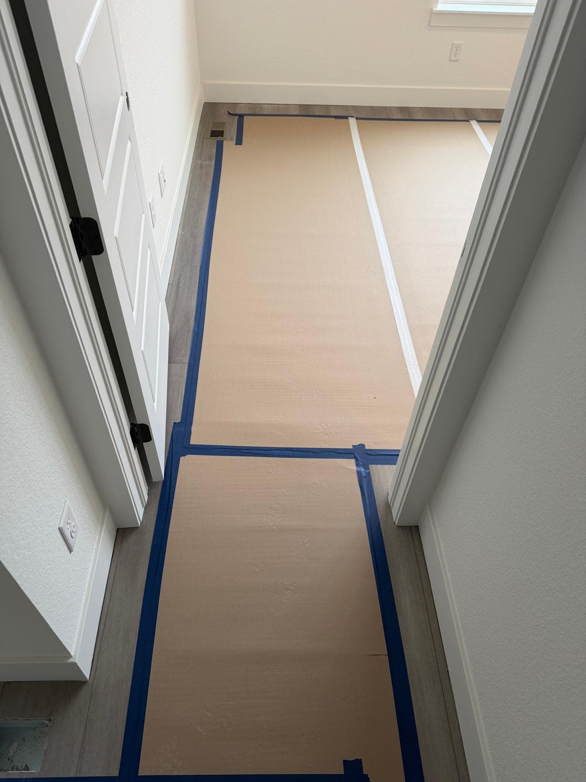 Floor protection paper and blue tape covering installed LVP